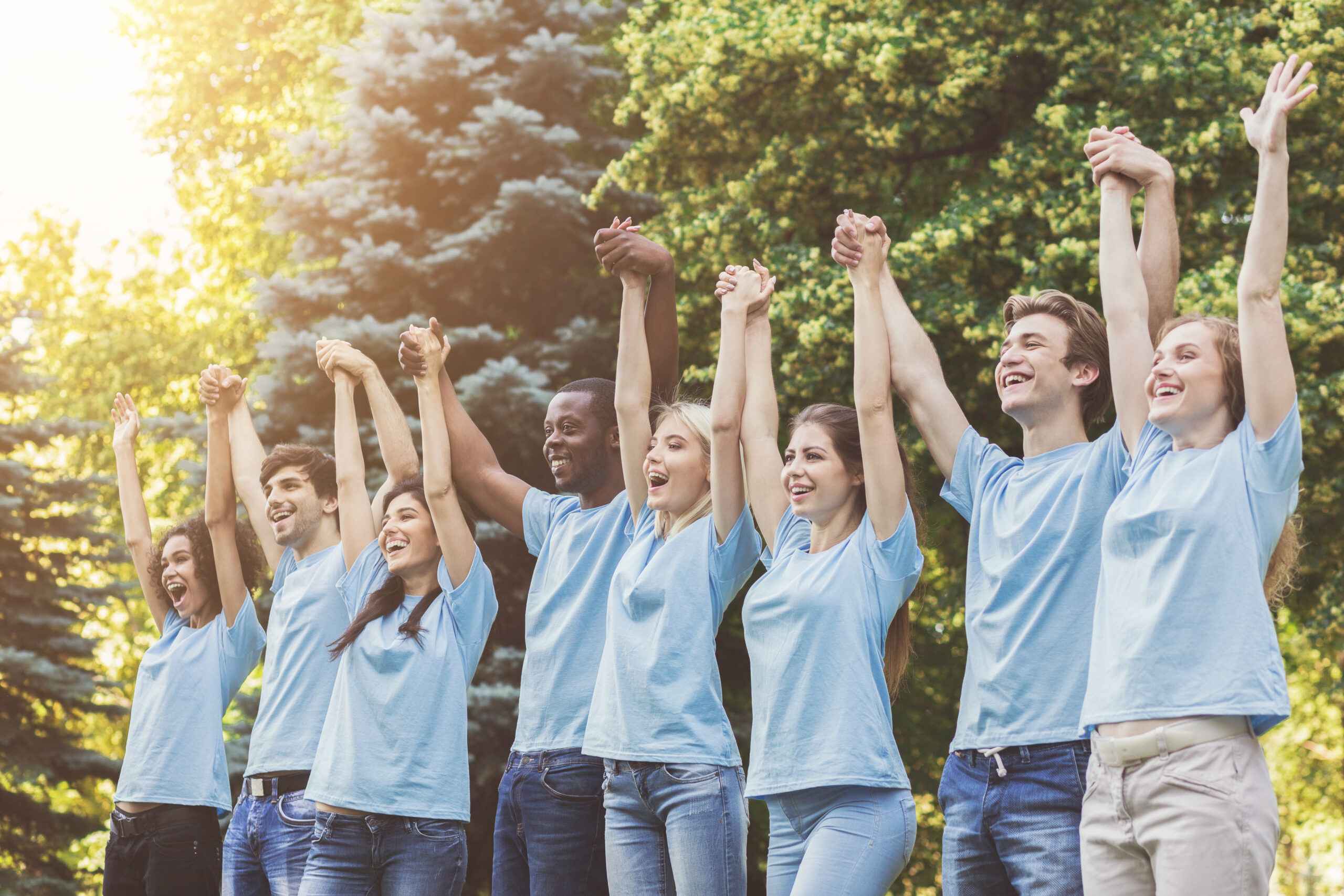 Group of young volunteers join hands in park